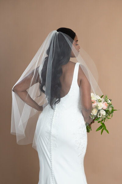 Bride wearing a simple classic bridal veil and holding a white and pink bouquet