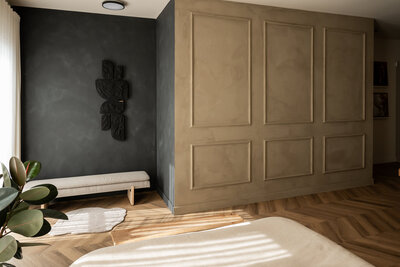 Stijlvolle brandingshoot in Studio Laurant, met een houten bankje tegen een zwarte muur en een handgemaakt kunstwerk als artistieke achtergrond.