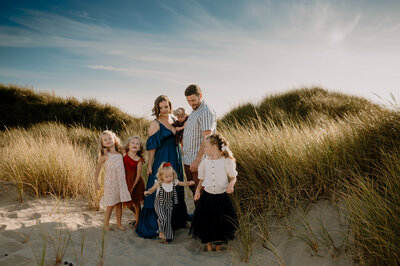 Family standing in tall grasses at the beach. All wearing dresses except Dad in striped shirt.