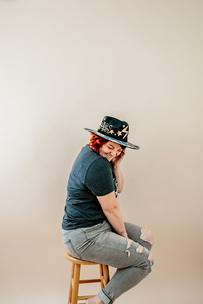 Aim True Photography sitting on a stool smiling with a harry potter shirt and hat on in a tacoma studio