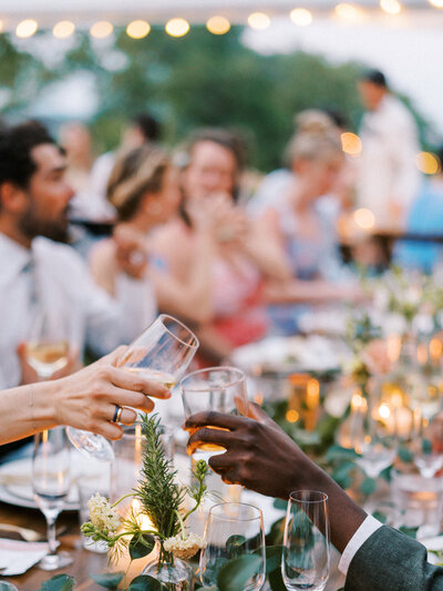 Hands toasting their glasses together at reception table