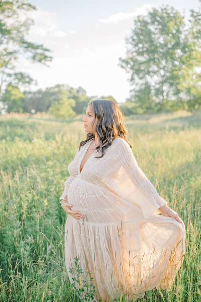 A stunning outdoor maternity session during golden hour, featuring a soon-to-be mom in a flowing light dress bathed in warm, golden light. Captured by Fairfield photography, this dreamy portrait highlights the beauty and anticipation of motherhood in a breathtaking natural setting