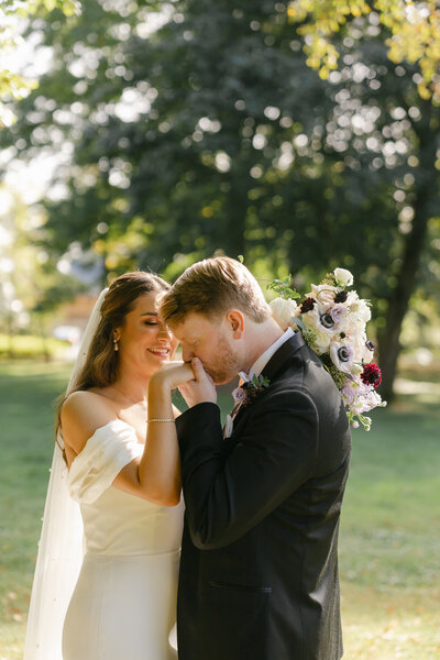 A women smiles and laughs underneath a veil as her fiance says something to her.