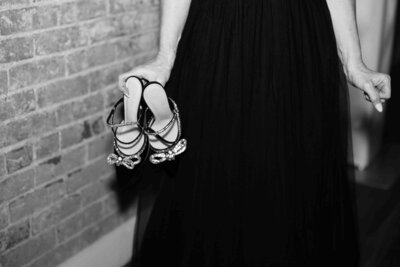 Bride holds up wedding shoes at reception