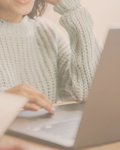 WOMAN IN MINT GREEN JUMPER TYPING ON LAPTOP