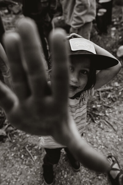 Playful child blocks the camera with hand during outdoor gathering in Breckenridge.