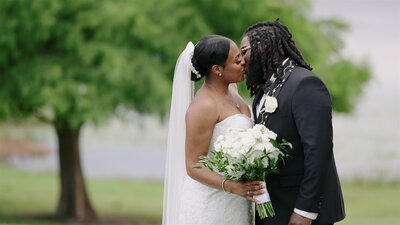 Haitian bride and groom kissing in front of a tree