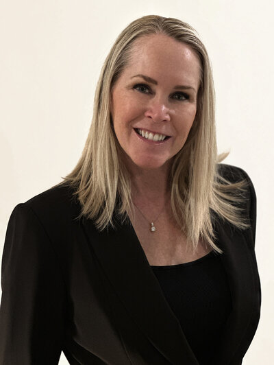 Headshot of Alana Crow, a woman with blonde hair and blue eyes wearing thick-framed black glasses and a black sleeveless top