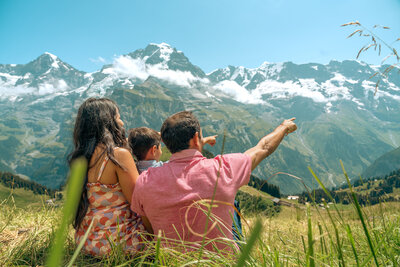 Eine glückliche Familie zeigt gemeinsam auf die majestätischen Berge über Lauterbrunnen, während sie die Schönheit der Natur geniesst.