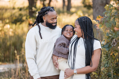 Family smiles together during a portrait session at a park in Aurora, IL, photographed by Kesha Wright.