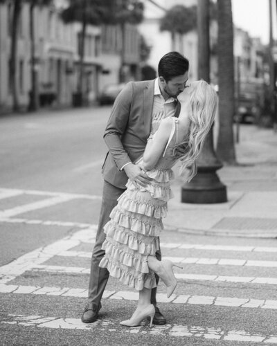 man and woman share a kiss while walking down a Charleston street.