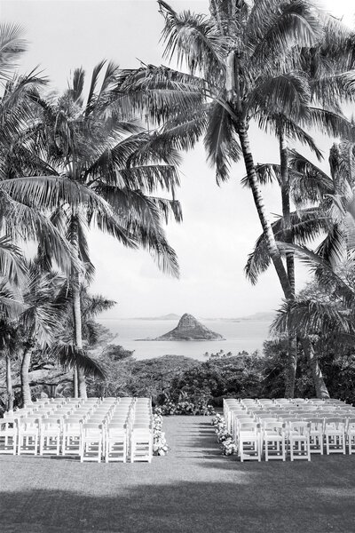 A wedding ceremony venue with white chairs overlooking the water 