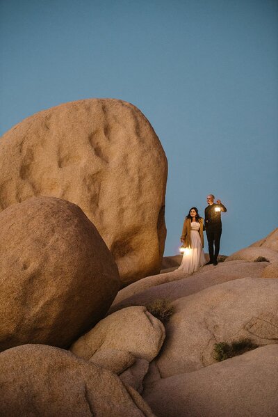 Eloping couple hugs while the sun rises on a mountain behind them