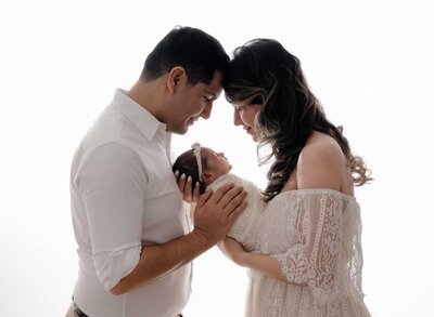 Family photo dressed in white and looking lovingly at their baby girl. Studio photo was taking in Marietta GA by Jenni Nikki Photography.