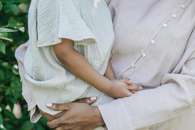 Mother holding child closely, hands clasped around child | Rooted Within supportive family evaluations