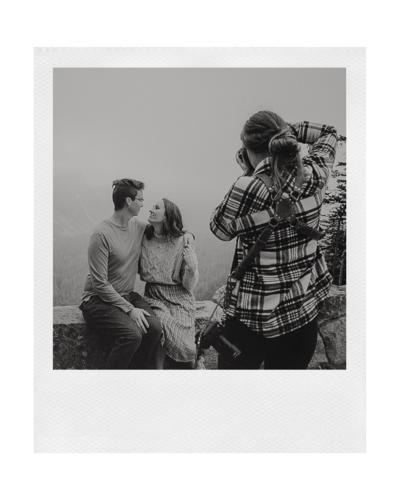 polaroid of a couple looking at eachother on an overlook in mount rainier national park while a photographer takes a photo of them