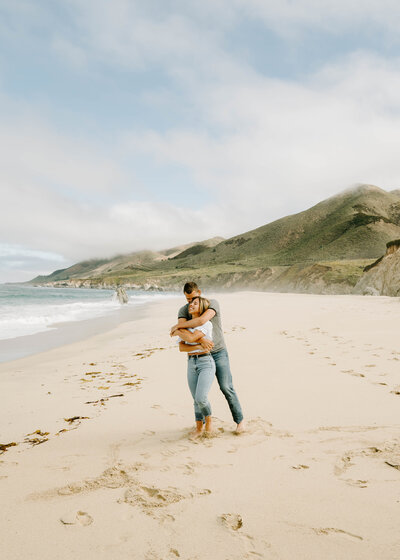 Couple cuddling on the beach in Big Sur