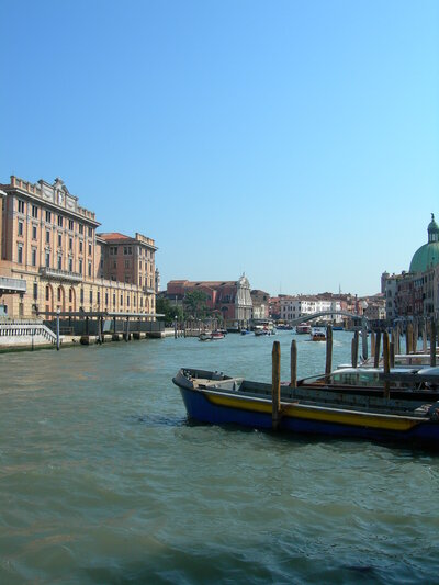 Venice canal on a clear day with blue skies & boats in the canal