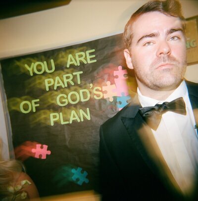 Groom in front of sign at wedding by 35mm film wedding photographer Noble Photo Co