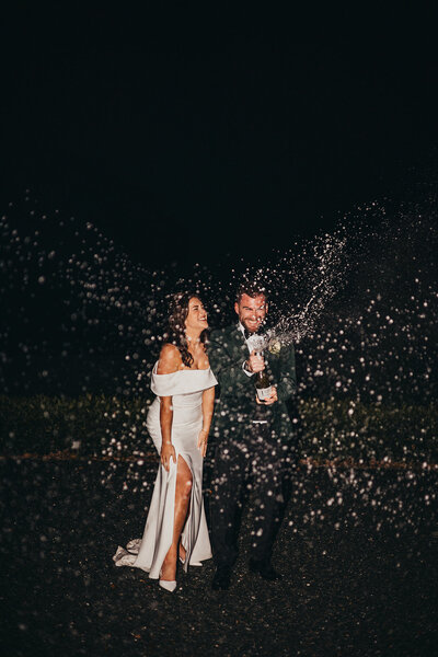 married couple spray champagne in celebration
