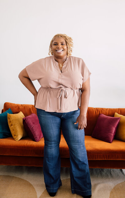black woman sitting on concrete steps wearing button down top with distressed jeans plus size  looking at cell phone