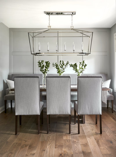Grey dining room with wall panel detail, darlana lantern light fixture, and upholstered dining chairs