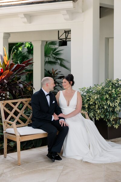 Bride and groom posing seated together outside a white villa