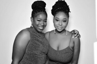 two women pose in the open air photo booth with GLAM package. black and white image