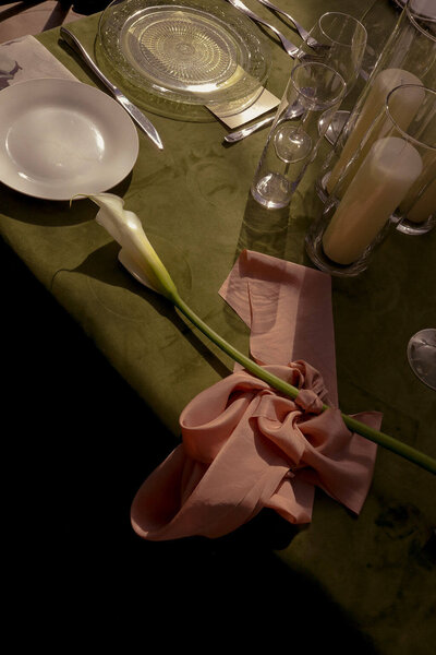 A table setting with place settings, a flower, and candles, representing the design details and rental options offered by Eugene wedding planners Birdie June. 