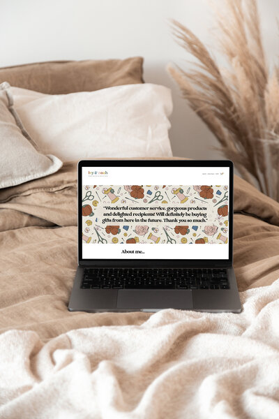 Laptop on bed showing branding illustrations created by TLPS on a website