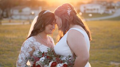 Two brides touching foreheads on a field