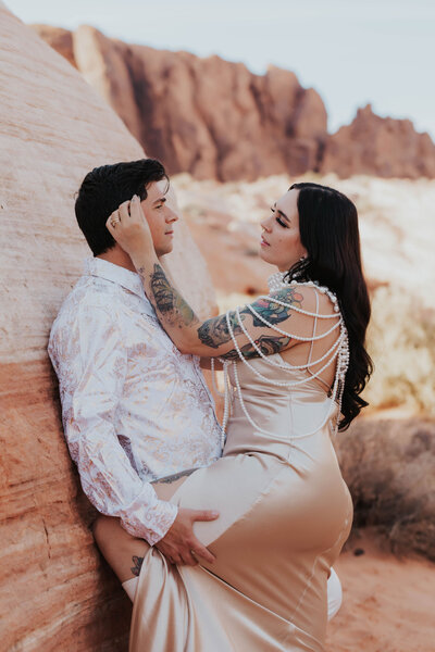 couple leans on red rock