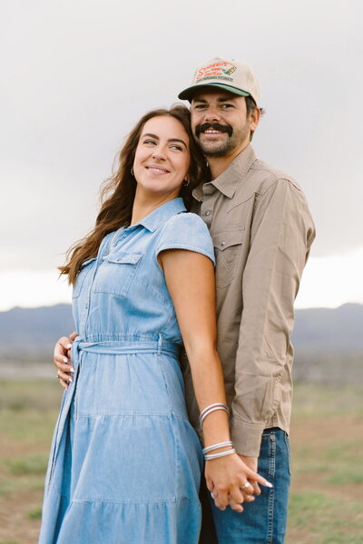 Engaged couple sharing kiss during windy mountain session
