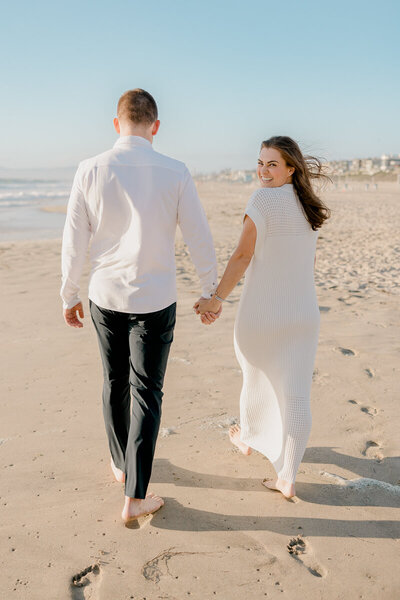 manhattan beach engagement photos on the sand by the pier in creamy neutral colors at sunset