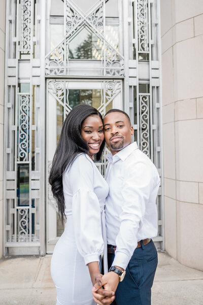 Black bride and groom posing in front of greenery for their engagement session. Photo taken at Volunteer Park in Seattle, Washington.