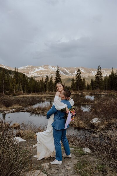 groom lifting bride with mountains and trees in background