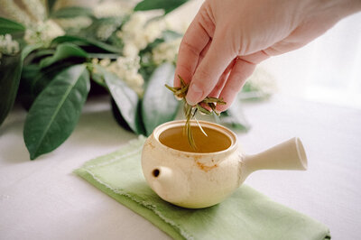 Tea leaves on a table with a tea cup in the background