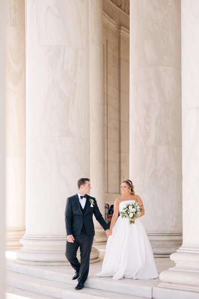 Bride and groom, walking between stone pillars in Washington DC.