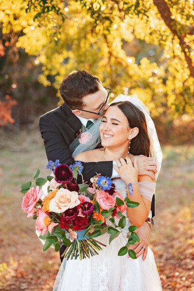 gorgeous fall sunlight falls on wedding portraits adorned with jewel toned florals