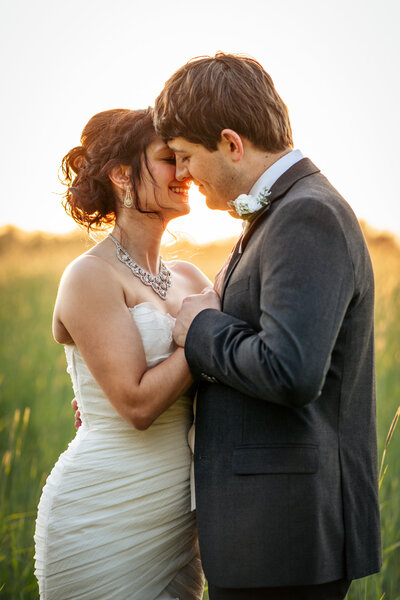 bride and groom kiss at golden hour in field at NC wedding