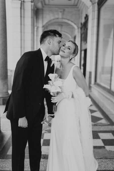 Groom kissing bride's cheek on Stephen Ave. in downtown Calgary