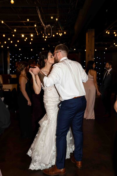 bride and goom kissing while dancing at wedding reception