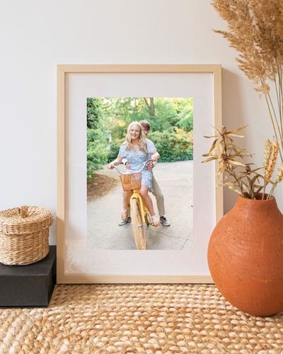 Greenville couple's printed photo in a frame on a side table. A vase with some brown plants and a wooden basket are also on the table. 
