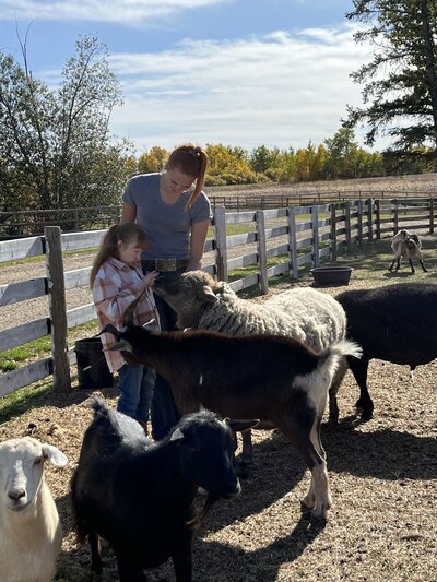 A woman guarding a child playing with a lamb at Spirit's Respite Ranch.