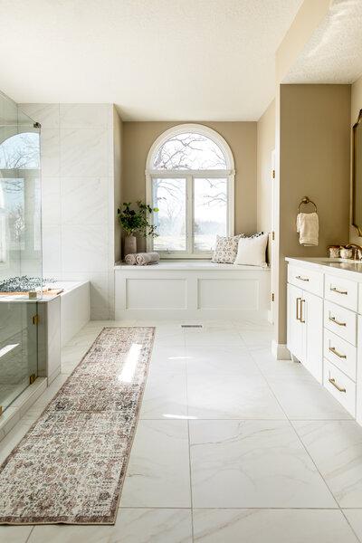 Bright and airy primary bathroom with walk in shower, soaker tub, window seating and large vanity located in Lake Ozark, Missouri.