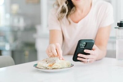 Close-up of a woman picking up chips from a plate of food on a table