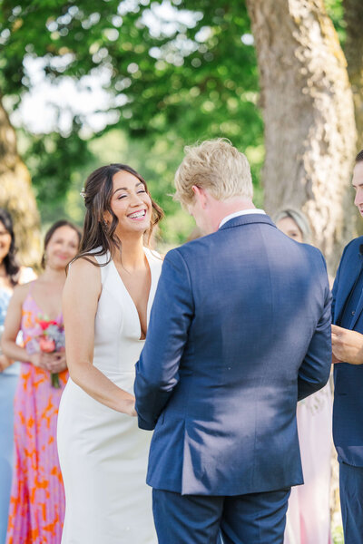 Man holds onto woman and she smiles over her shoulder as the golden sunset is behind them. Taken at a winery in Kentucky by cincinnati based wedding photographer.