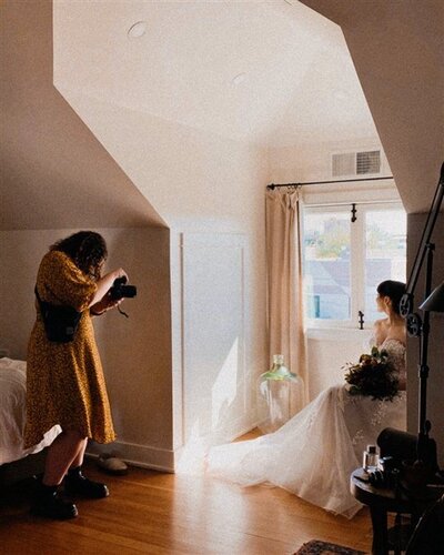 Andi captures an intimate moment of a person in a wedding outfit sitting by a bright window.