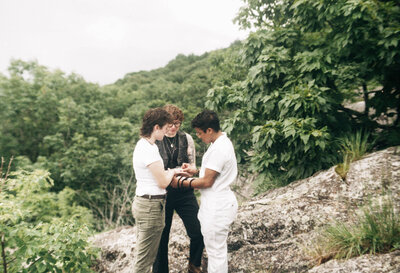 Bride and groom standing hand in hand with a mountain lake behind them during their intimate Virginia elopement, photographed in natural light and soft tones.

