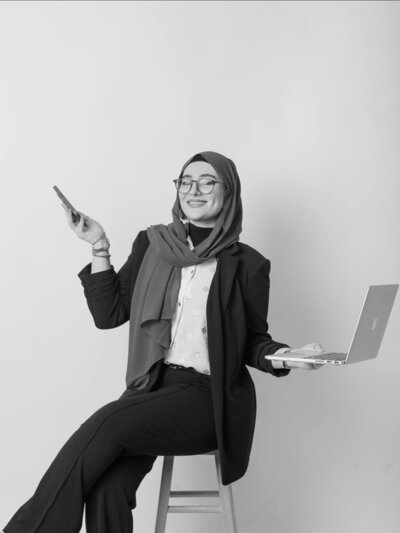 Ayah Official smiling while holding her phone, representing confidence and connection as a business mentor for women entrepreneurs